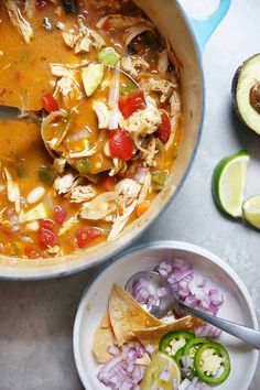 a bowl filled with chicken tortilla soup next to an avocado