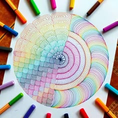 colored crayons surrounding a drawing with an intricate spiral design in the center, surrounded by smaller crayons