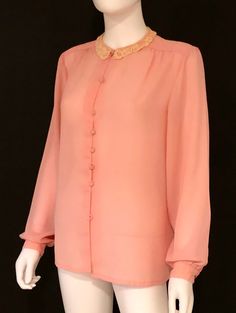 Vintage 1980s feminine long sleeve blouse in peach, featuring a delicate crocheted lace collar, pleating at shoulder tops, and a seven self covered button closure. Soft and with wonderful drape. Designer label removed; fabric label removed - feels like polyester. Retro feminine top, circa 1980s, is in excellent vintage condition. Bottom button missing; not visible when tucked in. Enjoy! *(International Buyers are welcome - however, please email me so I can check the shipping rate for you before Vintage Tops With Lace Trim And Peter Pan Collar, Vintage Orange Long Sleeve Blouse, Vintage Pink Tops With Button Closure, Vintage Orange Button-up Tops, 1970s Collared Tops With Button Closure, Victorian Blouse, Feminine Top, Fabric Labels, Lace Collar