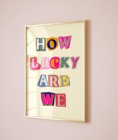 a framed poster with the words how lucky are we written in multicolored letters