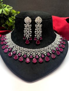 Gorgeous fine quality lab Ruby dark pink zircon and  diamonds studded necklace with white gold rhodium plating and matching Earrings Item contains: Necklace and earrings AAA quality cubic zirconia used. Highest quality and craftsmanship Necklace Fitting is adjustable Earrings Closure: Pushback Necklace Closure: chain with adjustable length Hook Details-  -Handmade item -Delivery from a small business in India -Materials: white rhodium, stones, cz, zircon, American diamond -Jewellery type: Earrin Hand Set Diamond Dangle Jewelry, Party Jewelry With Round American Diamond, Ruby Jewelry With Diamond Accents For Party, American Diamond Jewelry With Diamond Cut For Party, American Diamond Party Jewelry With Diamond Cut, Fine Jewelry Sets With Cubic Zirconia For Celebration, Diamond Drop Jewelry With Sparkling Stones, Fine Jewelry Sets For Celebration With Cubic Zirconia, Hand Set Silver Drop Jewelry