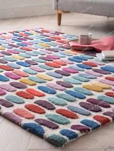 a colorful rug on the floor in a living room with a couch and coffee cup