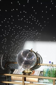 a mirror ball sitting on top of a table next to a vase and other items