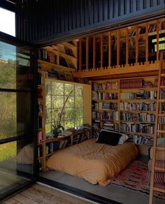 a bed sitting in the middle of a room next to a book shelf filled with books