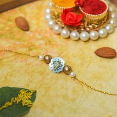 Surprise your brother with this exquisitely crafted rakhi on Rakshabandhan. This designer rakhi has a turquoise pendant of approximately one inch, decorated with golden thread work and small turquoise beads. It is woven on a golden thread with golden and white beads adorning the pendant on two sides. Order this exclusive rakhi online now! Rakhi Online, Golden Thread, Thread Work, One Inch, Turquoise Pendant, White Beads, Turquoise Beads, Pearl Necklace, Cool Designs