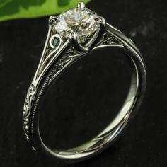 a white gold engagement ring with green stones