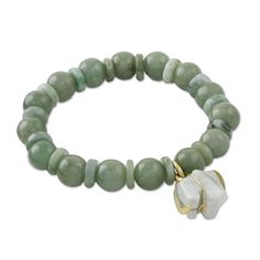 Paying tribute to Thailand's beloved symbol, artisan Somluck Komolmith adorns this bracelet with a carved jade elephant charm. The stretch bracelet is crafted from round and disc-shaped jade beads. The artisan secures the charm to the bracelet using polished gold plated sterling silver for an elegant accent. Jade, gold-plated sterling silver High polish finish Handmade in & fairly traded from Thailand Due to the handmade nature of this product, color may vary. Jade Elephant, Elephant Bracelet, Carved Jade, Different Shades Of Green, Elephant Charm, Jade Bracelet, Pretty Bracelets, Jade Carving, Bracelets Handmade Beaded