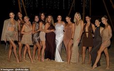 a group of women standing next to each other on top of a sandy beach at night