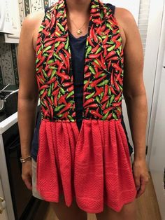 a woman standing in a kitchen wearing a red and green dress with an orange design on it