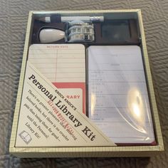 a personal library kit in a box on a bed with writing paper and other items