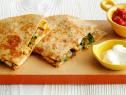 two quesadillas on a cutting board with salsa and sour cream