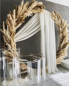 two vases with dried plants in front of a mirror