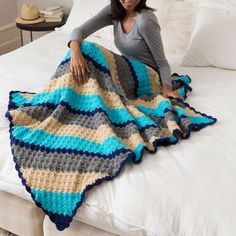 a woman sitting on top of a bed holding a blanket