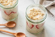 two jars filled with oatmeal sitting on top of a table next to wooden spoons