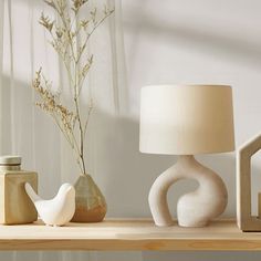 a table topped with a lamp next to a vase filled with flowers and other items