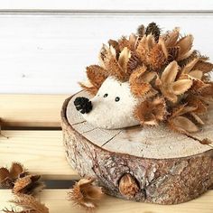 a hedgehog sitting on top of a tree stump next to some cones and nuts