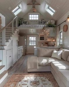 a living room filled with furniture next to a kitchen and stairway leading up to the second floor