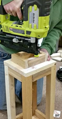 a person using a power tool on a piece of wood that is sitting on top of a stool