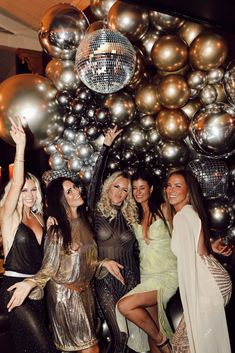 several women posing for the camera with disco balls in the background