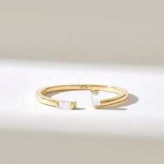 a gold ring with two square stones on it's sides, sitting on a white surface