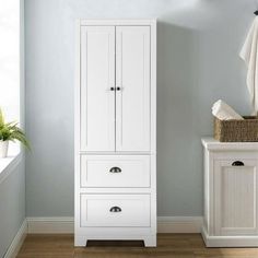 a white cabinet sitting next to a window in a room with blue walls and wooden floors