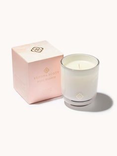 a white candle sitting next to a pink box