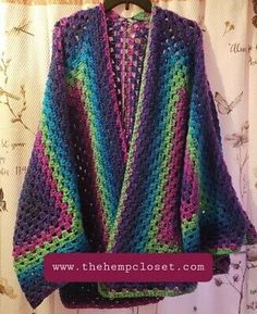 a colorful crocheted sweater hanging on a hanger