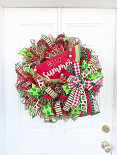 a wreath with the words hello summer on it hanging from a front door decorated for christmas