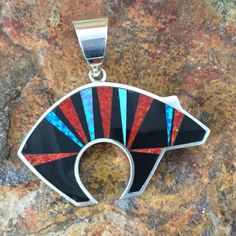 This beautiful Sterling Silver Bear Pendant, as part of the Red Moon Collection, features Black Jade, Kingman Turquoise and Blue, Green & Red Lab Opal. Dimensions: 1 3/4"W x 1 5/8" (Including Bale) The Pendant is designed by David Rosales, one of the finest contemporary Southwest Artists in the world. He is the founder and co-owner of Supersmiths, Inc. of Gallup, NM. Each Pendant is custom made and carries a lifetime guarantee. Artisan Red Jewelry With Inlay, Artisan Red Inlay Jewelry, Red Sterling Silver Jewelry With Inlay, Multicolor Pendant Inlay Jewelry, Multicolor Pendant Jewelry With Inlay, Multicolor Inlay Pendant Jewelry, Contemporary Southwest, Red Lab, Silver Bear