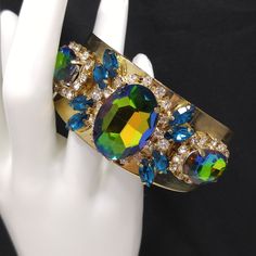 *Description: This is a gorgeous watermelon rhinestone crystal bracelet on a golden brass cuff which glitters and sparkles in the light. The vintage rhinestones are secured on a golden brass cuff and the reflective cuff adds additional sparkle to the bracelet. There is one large watermelon rhinestone in the center, surrounded by clear rhinestones and sapphire blue marquise cut rhinestones. On each side of the center stone are two more watermelon rhinestones, a little smaller in size, one on each Jeweled Party Bracelet, Party Jeweled Bracelet Jewelry, Luxury Jeweled Bracelet For Parties, Crystal Bracelet With Jewels For Parties, Crystal Bracelets With Jewels For Parties, Party Crystal Bracelets With Jewels, Glamorous Jeweled Bracelets For Party, Adjustable Jeweled Crystal Bracelet For Parties, Green Stone Bracelets For Party