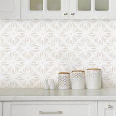 a kitchen with white cabinets and wallpaper on the counter top, along with two mugs