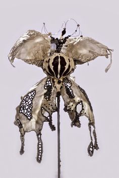 an insect sculpture is shown on top of a metal pole with holes in the middle