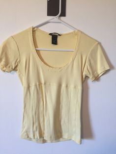 Pale Yellow Short Sleeve Round Neck Women's Top Brand: Moda International Size: small Material: 100% cotton  Soft and comfy shirt  length is just at waist or slightly cropped Hanger not included. Previously Worn. We recommend all clothing purchased be cleaned before wear.  These are vintage finds discovered and sold as is. ALL SALES FINAL!!  NO RETURNS!! Affordable Vintage Yellow Shirt, Spring Cotton T-shirt With Stretch, Stretch Cotton T-shirt For Spring, Y2k Short Sleeve Cotton Shirt, Fitted Cotton Tops For Spring, Fitted Cotton Lounge Tops, Fitted Cotton Tops For Loungewear, Fitted Cotton T-shirt For Spring, Fitted Short Sleeve Shirt For Loungewear