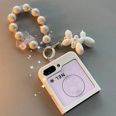 a cell phone case is attached to a beaded bracelet with flowers and stars on it