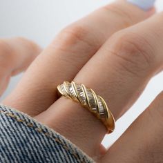 a woman's hand wearing a gold ring with three curved bands on it,