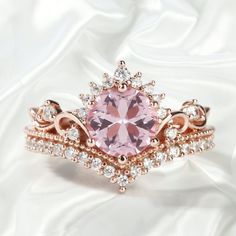 a pink diamond ring set on top of a white satin surface with diamonds around it