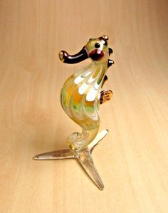 a glass figurine is sitting on a wooden table with its legs spread out