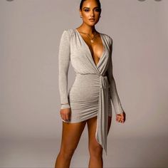 a woman is posing in a grey dress