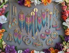 a bunch of different types of earrings and necklaces on a table with flowers in the background