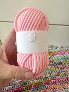 a hand holding a pink ball of yarn