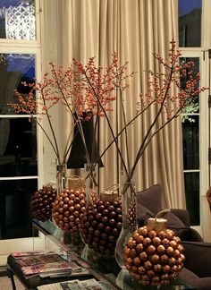 a table topped with vases filled with flowers and nuts on top of a glass table