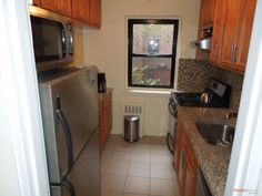 a kitchen with stainless steel appliances and wooden cabinets, along with tile flooring that matches the walls