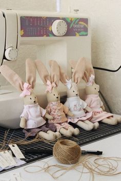 four bunnies sitting on top of a table next to a sewing machine