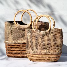 Gorgeously woven, this palm fiber handbag is truly one-of-a-kind. Made from locally sourced palm, this environmentally friendly handbag features fabric a cotton lining with small pockets within to keep your essentials organized! Palm fiber & cotton Lined handbag 1 interior zipper pocket 2 interior open pockets Small: 8" H x 10" L x 3.75" D (20.3 x 25.4 x 9.5 cm) Large: 10" H x 12" L x 3.5" D (25.4 x 30.5 x 8.8 cm) Handmade in & fairly-traded from Bangladesh Eco-friendly Beach Bag With Braided Handles, Eco-friendly Woven Bucket Bag With Top Handle, Natural Fiber Bucket Bag With Bamboo Handle, Top Handle Natural Bucket Bag For Market, Natural Top Handle Bucket Bag For Market, Eco-friendly Rectangular Natural Shoulder Bag, Jute Bucket Bag With Braided Handles For Market, Natural Woven Fabric Bags For Vacation, Woven Jute Basket Bag