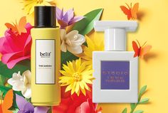 two bottles of perfume sitting next to each other on a yellow background with colorful flowers