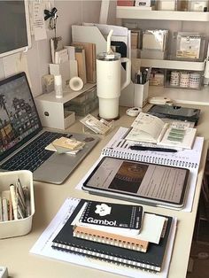 a laptop computer sitting on top of a desk next to books and other office supplies