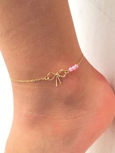 a woman's foot with a gold chain and pink beaded ankle bracelet on it