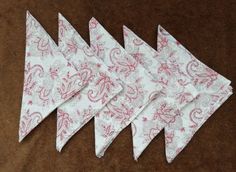 four white and pink bandannas sitting on top of a brown table