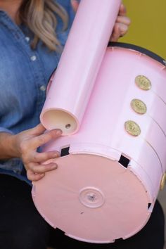 a woman is holding a pink object with buttons on it