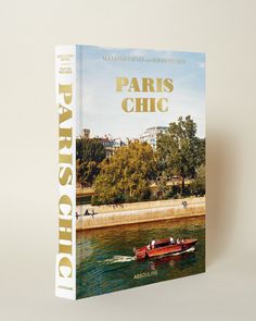 the book paris chic is on display in front of a river with boats and people